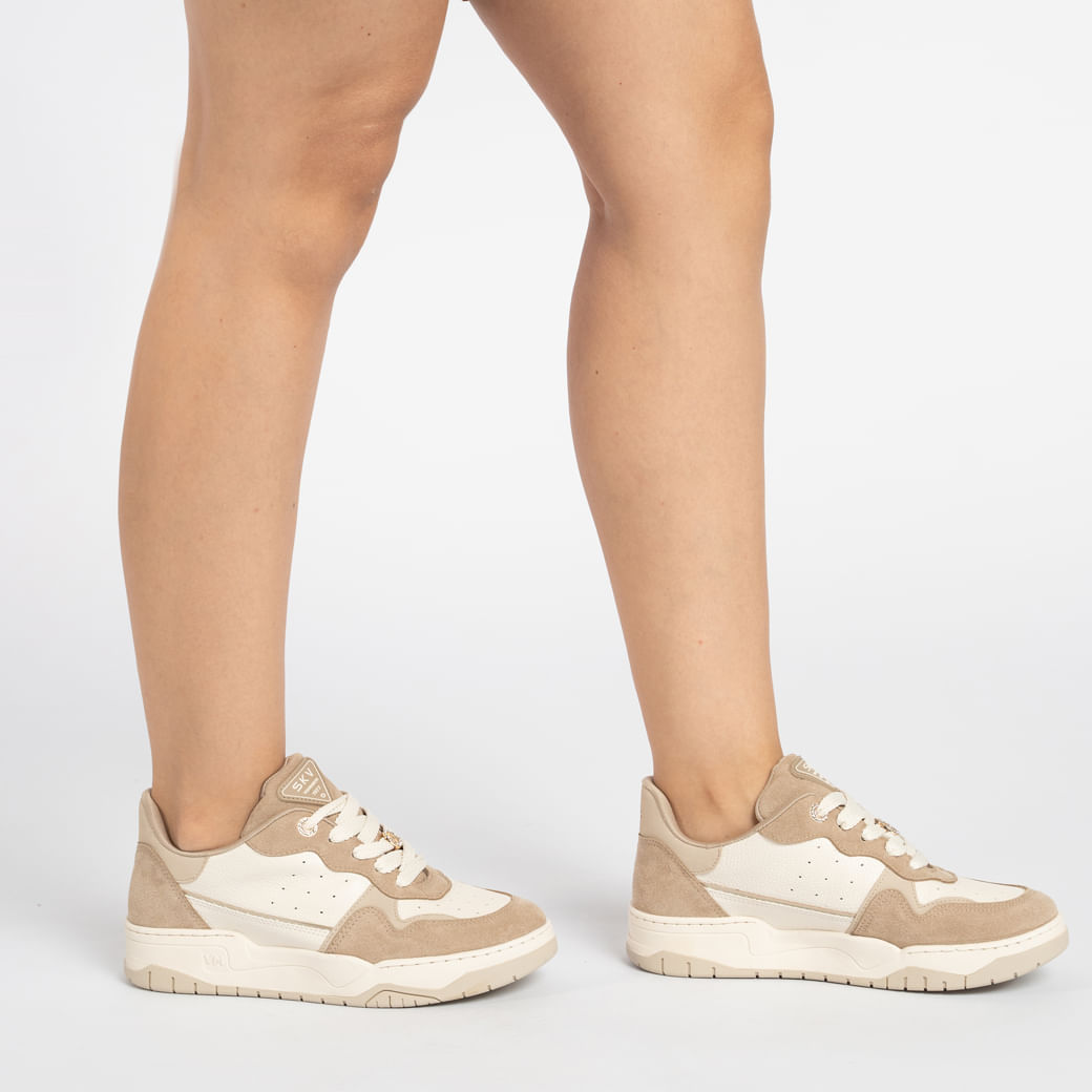 Tênis casual feminino Via Marte em camurça bege visto de lado, mostrando detalhes do cadarço e sola